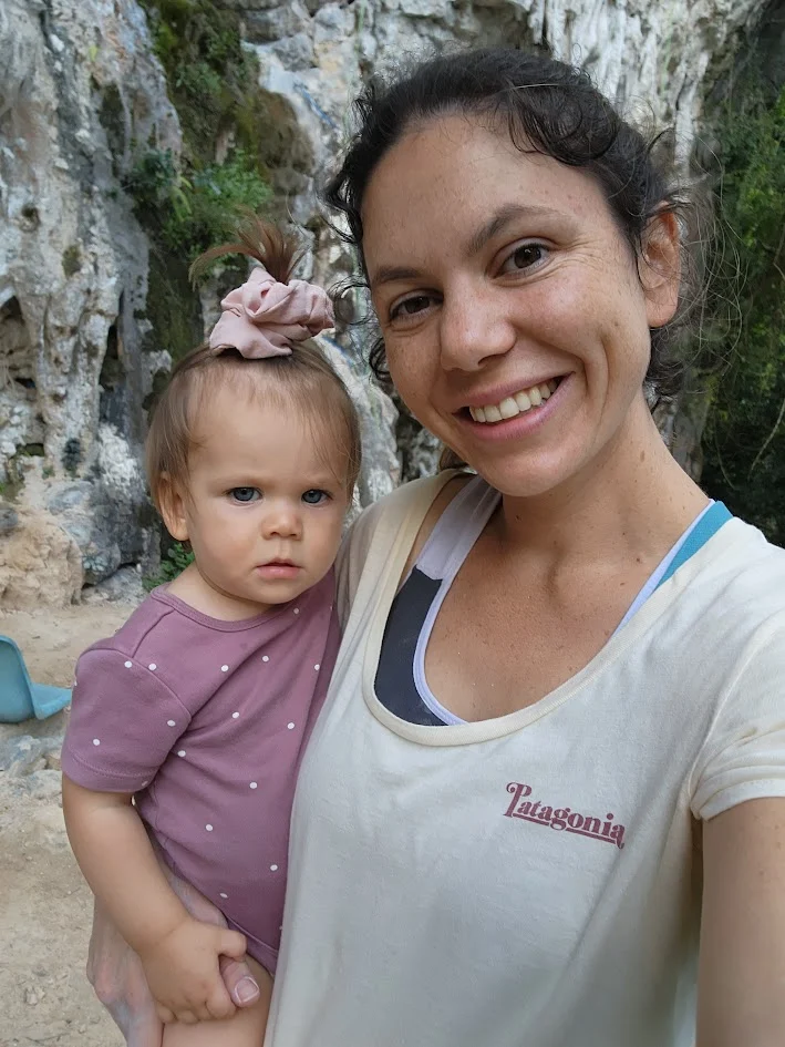 mum smiling holding her baby taking an authentic selfie in front of a cliff face