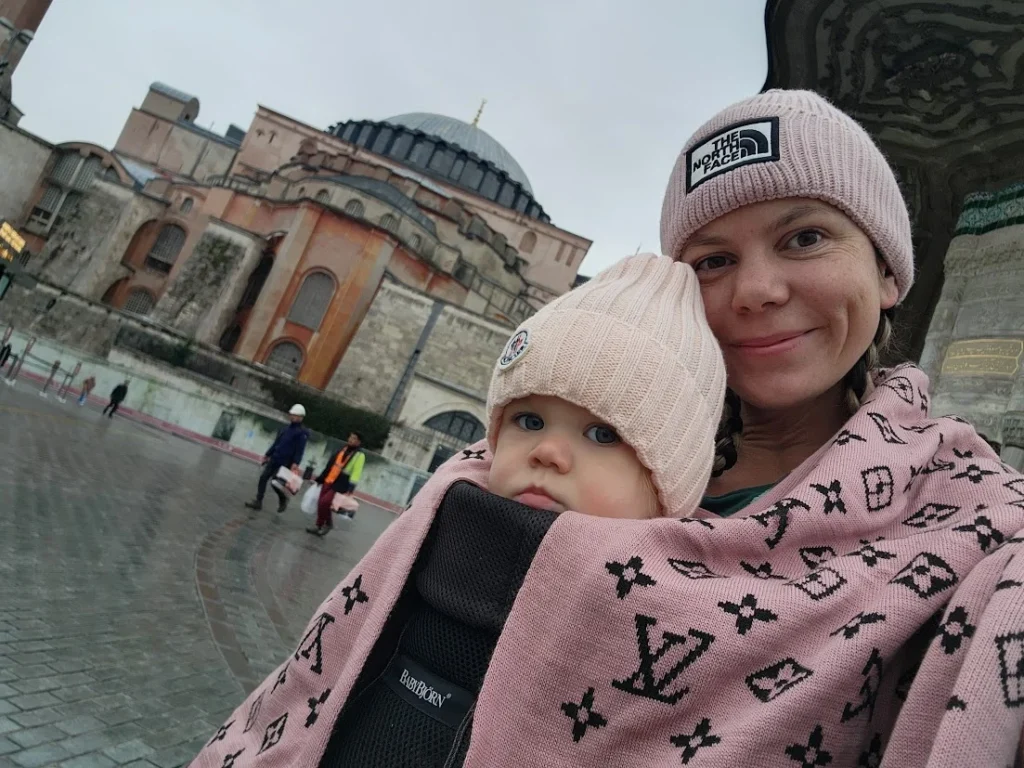 mum holding her baby visiting the blue mosque in istanbul