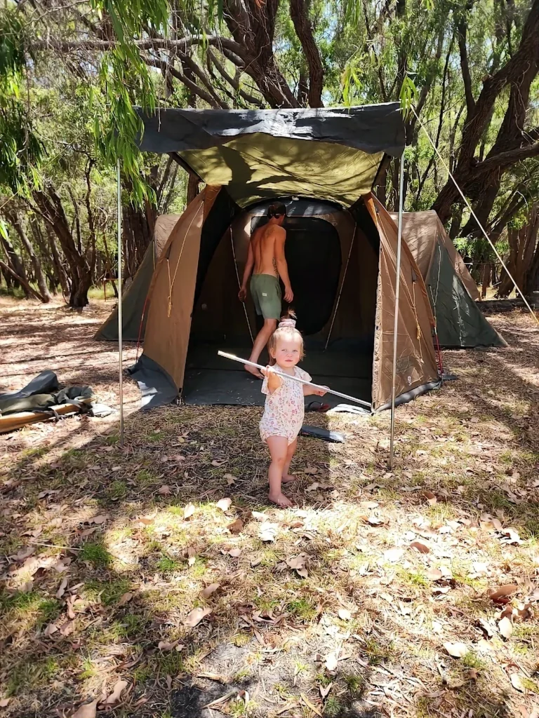a baby standing out the front of her family tent in australia