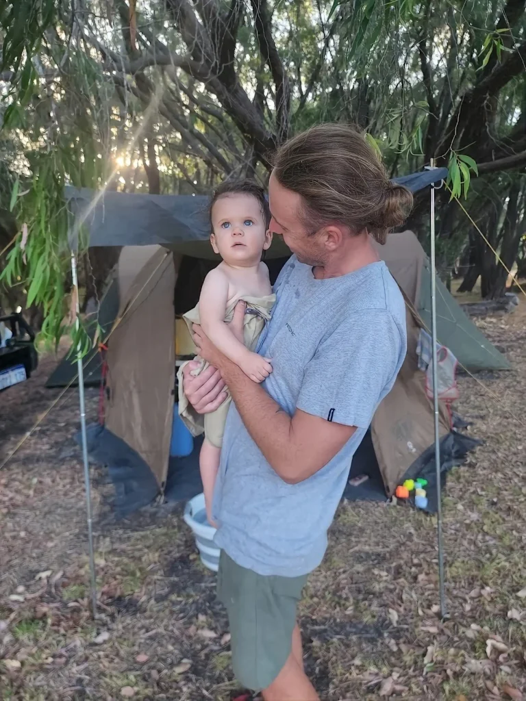 dad holding his baby camping in front of a tent in australia