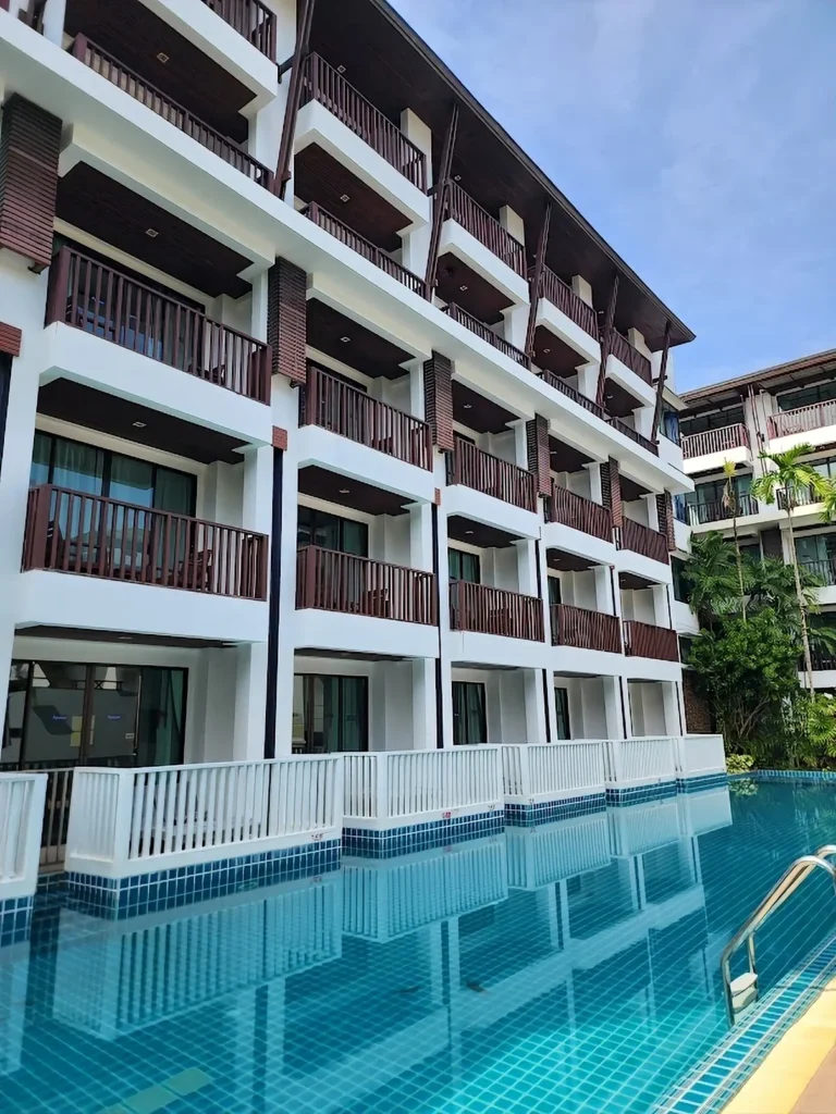 An outdoor photo of the Ao Nang resort pool at sunset with palm trees and mountain backdrop. A toddler