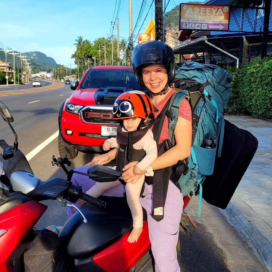 mum riding a bike in thailand with her baby and climbing gear they are both smiling