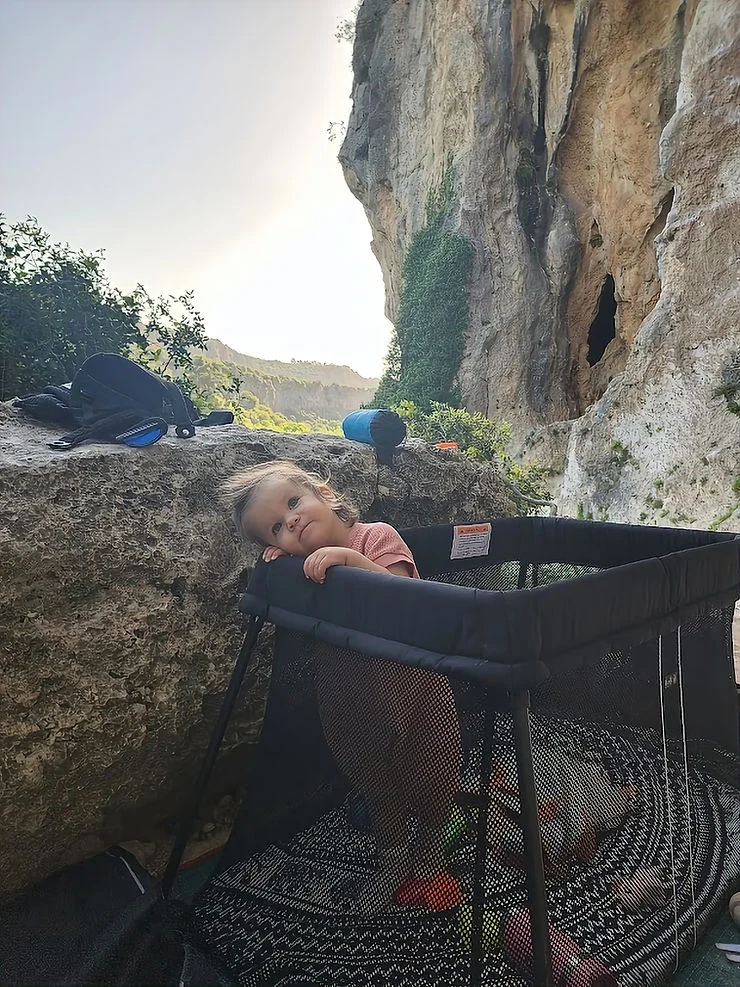 a little girl out in the mountains playing in her portacot
