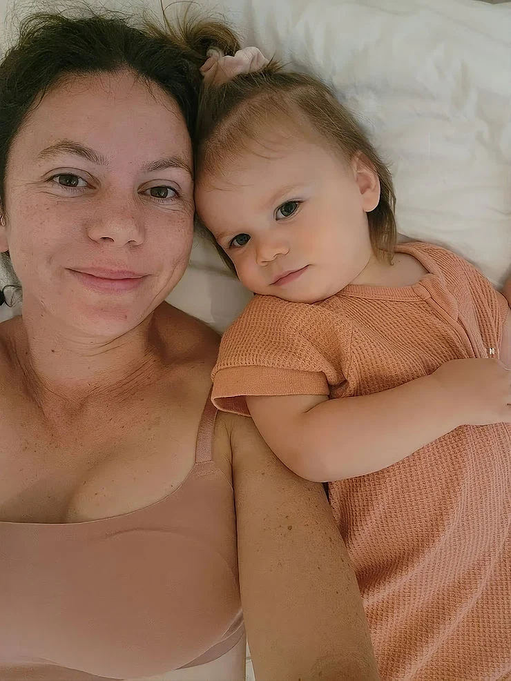 a mumma and her daughter laying on the bed cuddling and smiling