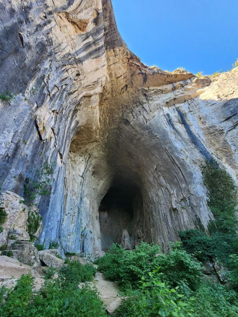 Wide shot of the Prohodna Cave entrance with morning light filtering in