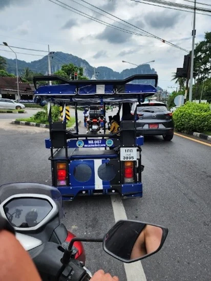 driving on a scooter behind a tuk tuk in thailand