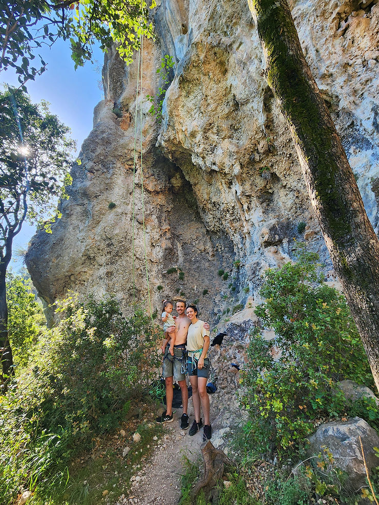 mum and dad standing in front of a memorable rock climb holding their daughter smiling