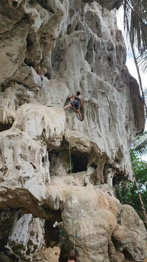 A girl rock climbing on a tall limestone cliff. Another of her from a different angle, focused and calm on the wall.