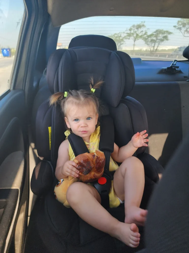 a little girl sitting in the back of the hire car eating an olive bread in turkey