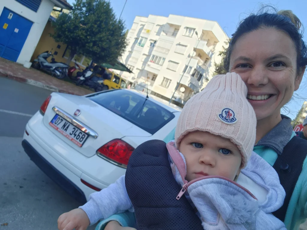 mum holding baby standing in front of the hire car in turkey