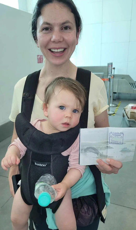 mum holding her baby in the airport with her first passport stamp