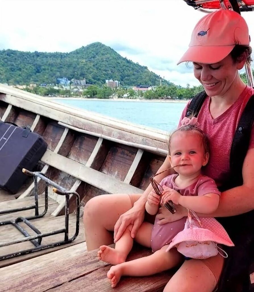 mum smiling looking down at her baby on a longtail boat in thailand